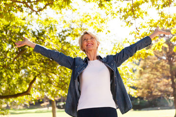 mid age woman with arms outstretched outdoors
