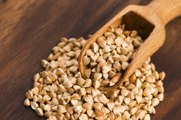 Buckwheat with a spoon on a wooden boards background