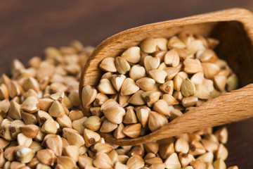 Buckwheat with a spoon on a wooden boards background