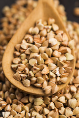 Buckwheat with a spoon on a wooden boards background