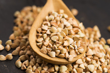 Buckwheat with a spoon on a wooden boards background