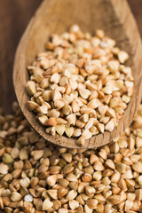 Buckwheat with a spoon on a wooden boards background