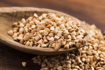 Buckwheat with a spoon on a wooden boards background