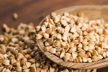 Buckwheat with a spoon on a wooden boards background