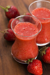 A glass of strawberry smoothie on a wooden background