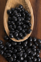 A lot of black soybeans on wooden background