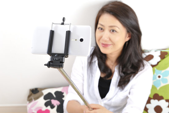 自撮り棒（セルフィー）で自分を撮影している日本人女性