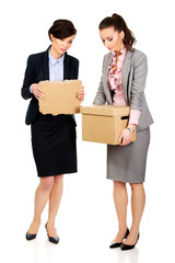 Two sad businesswoman carrying box.