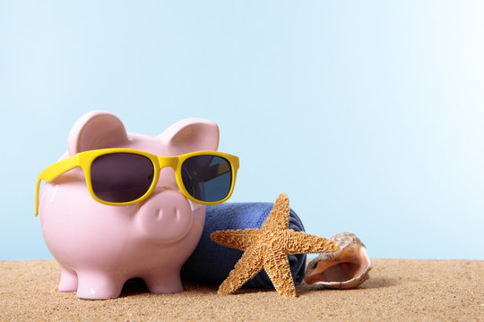 Piggy Bank or piggybank wearing sunglasses standing on a sunny tropical beach with towel holiday vacation retirement saving money plan photo