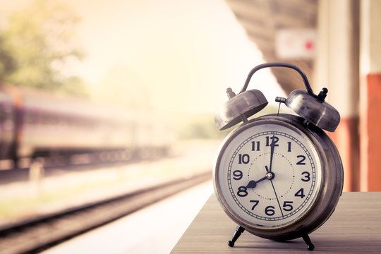 retro alarm clock on table on blur railway station background  i