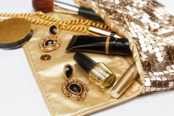 Golden woman accessories. Make up pieces, jewelry and shiny purse. Top view.