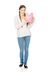 Teenage woman holding piggybank.