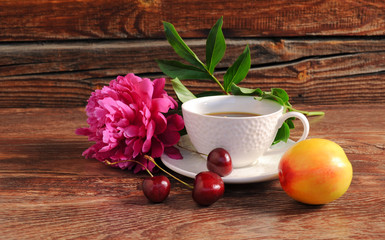 Peony, a cup of coffee, cherry and peach on a wooden background