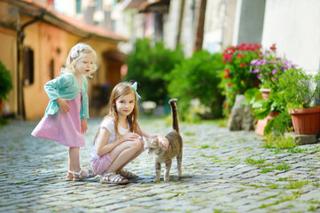 Two adorable little sisters and a cat