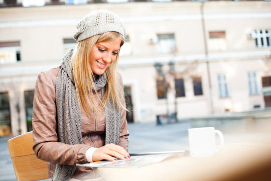 Happy girl reading magazine in a sidewalk cafe