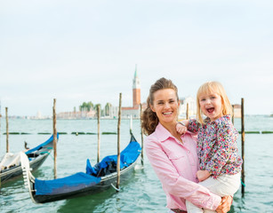 Fototapeta na wymiar A happy mother holding her daughter in her arms in Venice