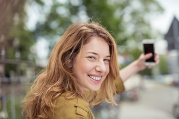 junge frau fotografiert sich mit ihrem handy in der stadt