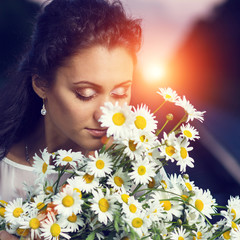 Toned image of young beautiful dreamy women with bouquet of flowers.