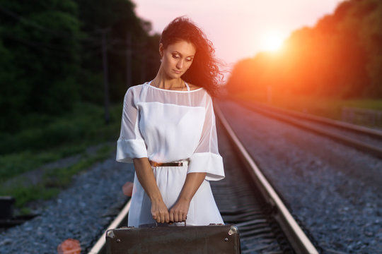 Young beautiful woman in white dress holding a suitcase