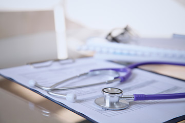 Purple stethoscope on the glass desk