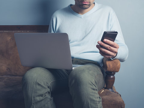 Man on sofa with laptop and smart phone