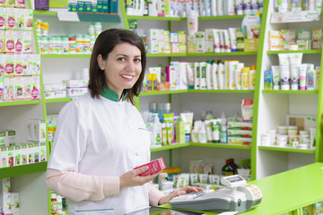 Young female pharmacist at cash register
