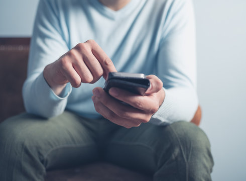 Young man sitting on sofa and using smart phone