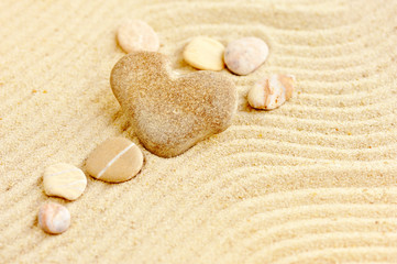 Fototapeta na wymiar Heart shaped stone is on sand