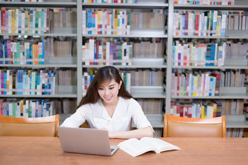 Beautiful asian female student using laptop for study in library