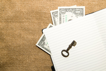 Opened notebook, key and money on the old tissue