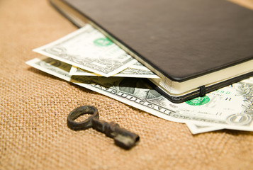 Opened notebook, key and money on the old tissue
