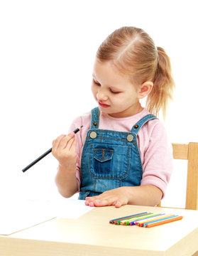 little girl in kindergarten is considering the pencil sitting on