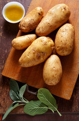 new potatoes on the old wooden background. with sage & olive oil