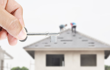 Hand holding key on house  background