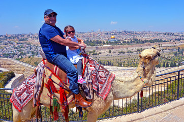 Tourists ride a camel against the old city of Jerusalem, Israel.
