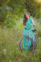 Fototapeta na wymiar beautiful young woman with an old bicycle in the field