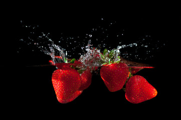Strawberries splashing into water