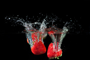 Strawberries splashing into water