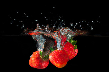Strawberries splashing into water