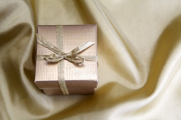 Golden box with ribbon on golden silk