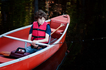 Fototapeta premium boy wearing a lifejacket fishing in a canoe