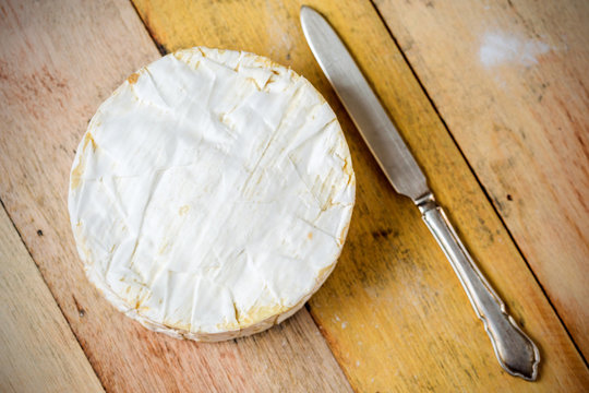 Camembert cheese and vintage knife on wooden table