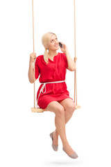 Beautiful girl talking on phone seated on a swing