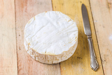 Camembert cheese and vintage knife on wooden table