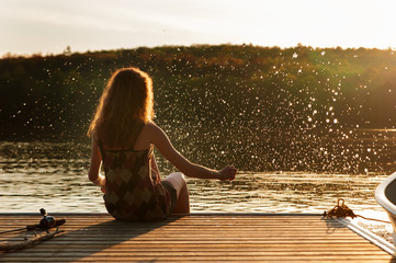 teenage girl splashing in a lake at sunset