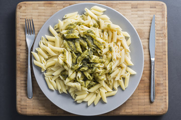 Pesto penne pasta dish on a wood background