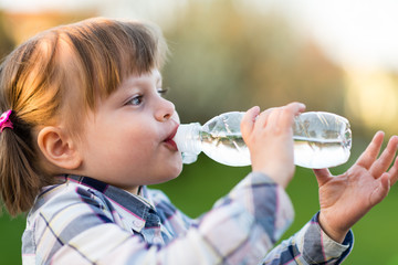 Girl drinking water. Cute little girl drinking water outdoor - very shallow deep of field (girl's...