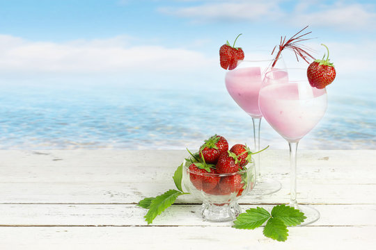 Strawberry cocktail on wooden table with beach background