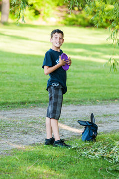 boy playing disc golf at a park on a summer day