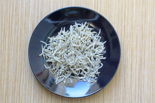 Anchovies or ricefish in black disk.

